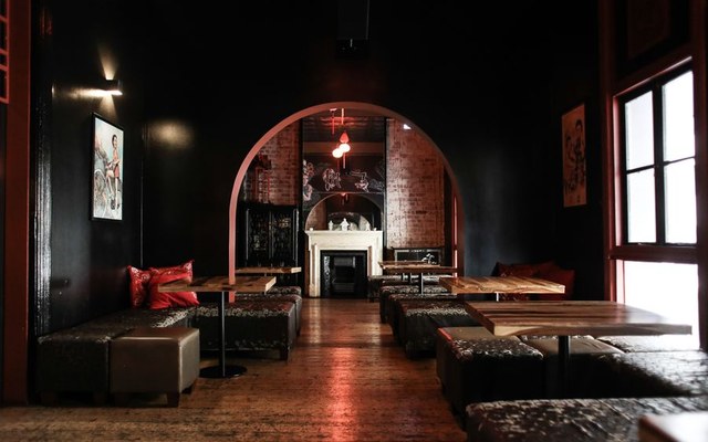 A blurred black-and-white hotel bar with low banquettes and an arched doorway